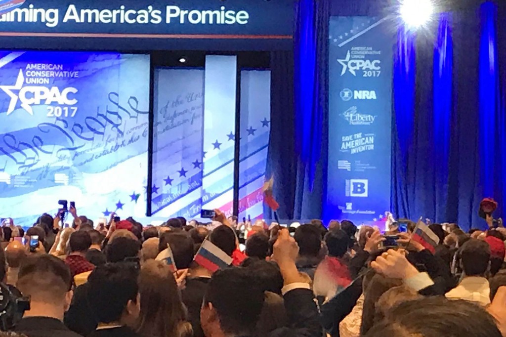 CPAC attendees waives Russian flags as part of a hoax.  Image Source: people.com