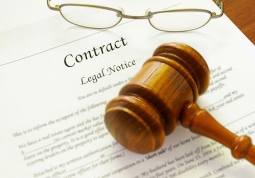 Picture of a Wooden Gavel and a Pair of Glasses Lying on a Legal Contract