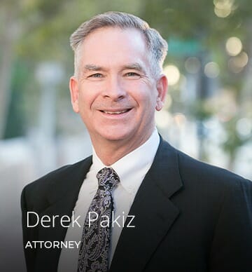 Derek pakiz injury attorney posing in suit in from of OC office