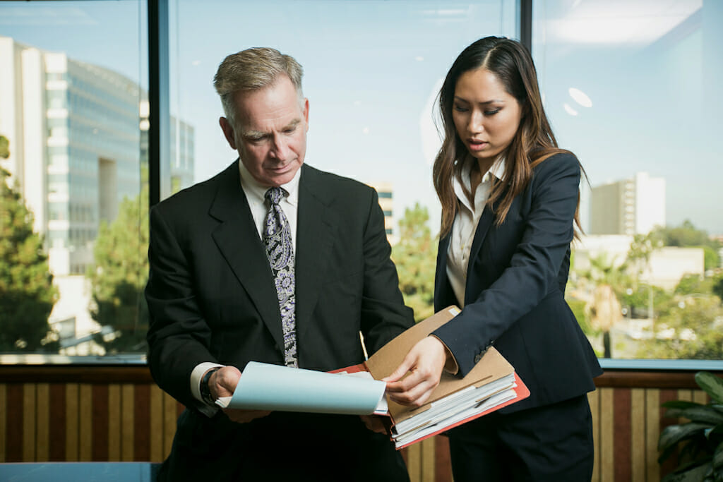 Derek Pakiz and Caroline attorneys in Riverside reviewing case in front of window