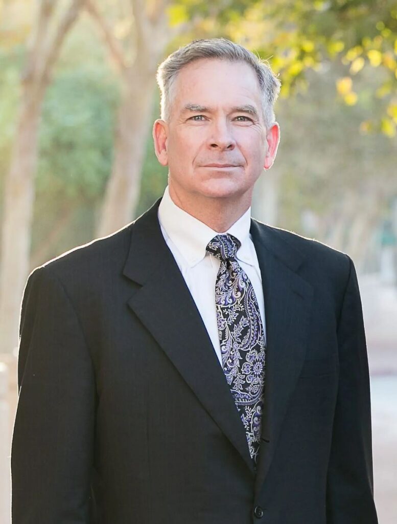 derek pakiz attorney in front of green trees background